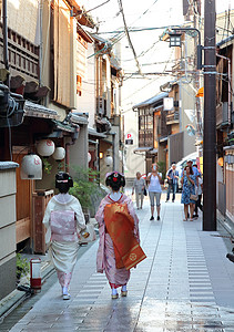 宫斗素材一位艺妓和Maiko在下午走过Miyagawacho街区的街道背景