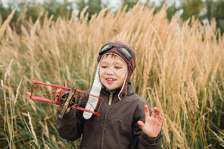 一个男孩在玩一架红色飞机男孩在田地图片