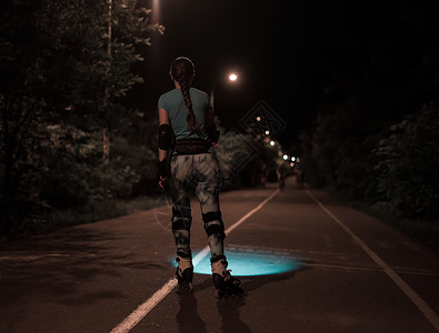 运动过路女孩在晚上用手电筒或火炬滑冰图片