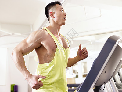 亚洲男健美运动员在健身房的跑步机上跑步图片