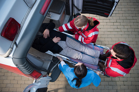 医护人员将救护车担架上的人抬上车的俯视图图片