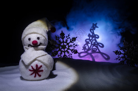 新年雪人卸下新年礼物晚上背景上被圣诞树包围的白色雪人玩具装饰图片