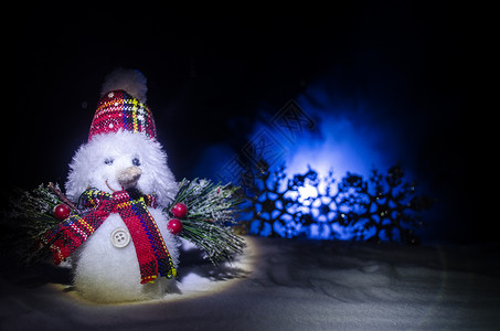 雪人卸下礼物晚上背景上被圣诞树包围的白色雪人玩具装饰图片