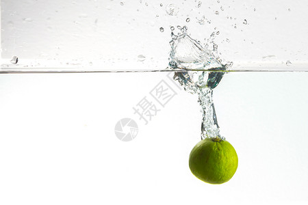 绿色柠檬滴直到水溅起背景图片