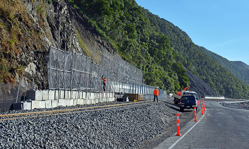 工人在今天公路一号开通之前急于完成路边岩背景图片