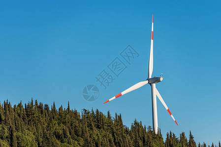 白色和红色风力涡轮机在清澈的蓝天与树木可持续资源图片