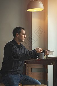 穿着休闲服的年轻人坐在咖啡馆里喝咖啡男人在咖啡馆喝咖啡温馨的气氛着图片