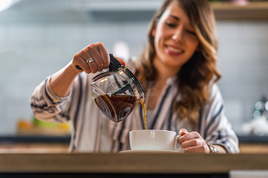 从水壶里倒咖啡的女人图片