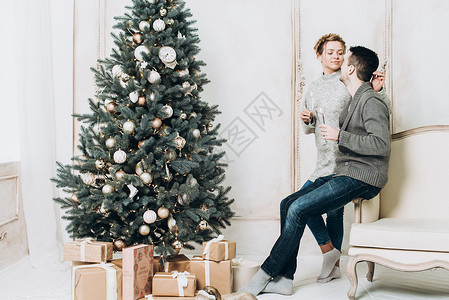 带圣诞装饰品的快乐情侣在白室享受圣诞图片