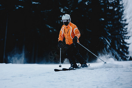 山坡上的男滑雪者背景是冰冻的黑暗森林冬季森林山滑雪图片