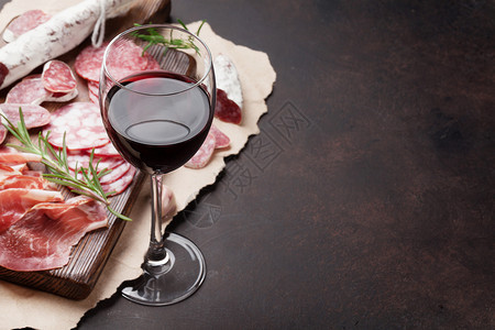 Salami切片火腿香肠熏肉培根和红葡萄酒杯图片