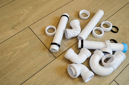 白色塑料管道管道光滑和弯曲配件法兰橡胶垫圈在米色板的背景下背景图片