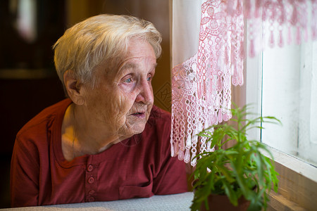 老妇人怀着向往的目光望向窗外背景图片