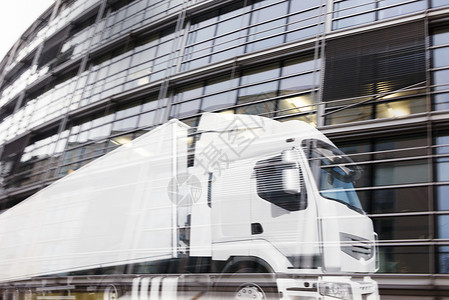 快速的白色卡车反映在摩天大楼上双重曝光图片