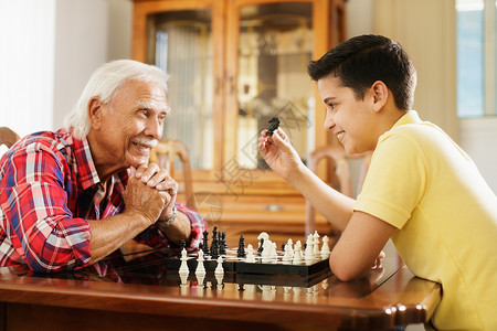 快乐的小孩在家里和老人下棋与祖父和孙子的家庭关系爷和男图片