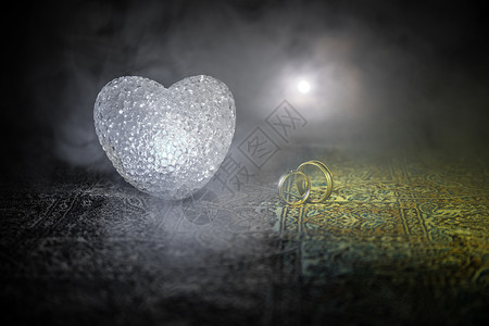 与黄金结婚戒指和心的求婚情人节的概念深色调的雾背景背景图片