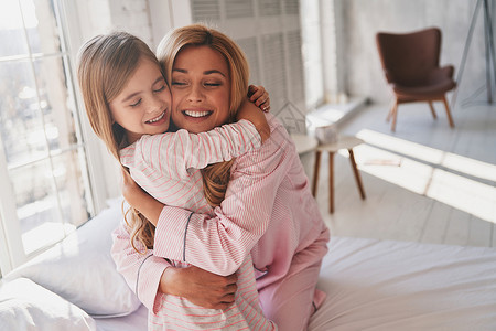 可爱的小女孩抱着她妈坐在家里睡觉图片