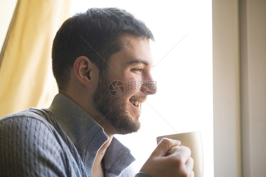 年轻的胡须拿着陶瓷杯子喜欢他早上喝咖啡或茶的气图片