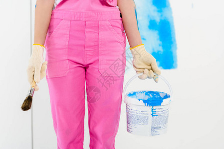 女孩拿着油漆刷子和涂漆桶的女图片