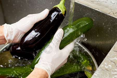 在水槽里用茄子冲洗西葫芦厨师手戴着白手套在水槽里洗菜背景图片