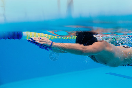 白种人运动员用肩胛骨在水下游泳池游泳图片