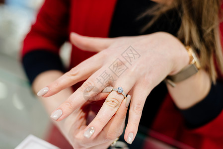 一家豪华珠宝店的女卖家展示了一枚戒指购买订婚戒指珠宝背景图片