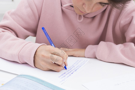 孩子的手在课桌或家里学习和写作图片
