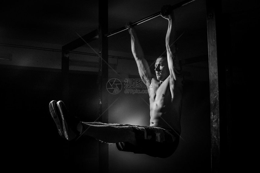 男人在十字栏上为手的肌肉做锻炼图片