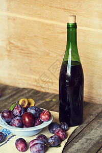 一瓶梅酒与木制背景上的新鲜李子图片