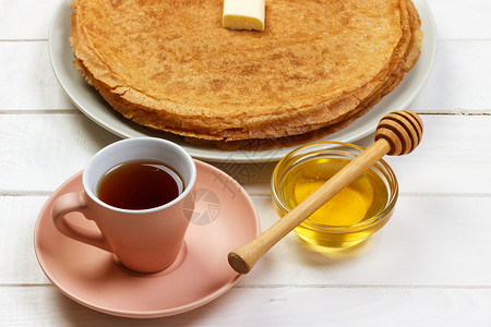 早餐茶配煎饼和木制背景的蜂蜜图片