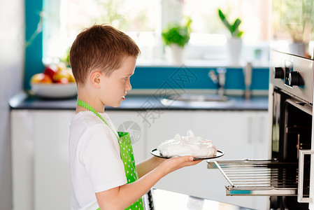 快乐的孩子把蛋糕放到烤箱里孩子在帮忙图片