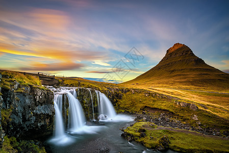 著名的柯尔朱弗斯福瀑布的夏季日落和在冰岛背景中的柯尔丘费尔图片