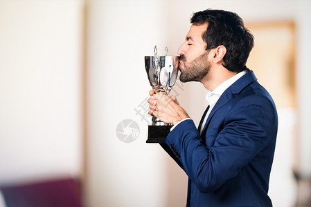 英俊的男人拿着一个奖杯在图片