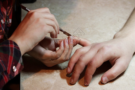 参加修指甲培训课程的学生将男客户的手钉上一个外形背景图片