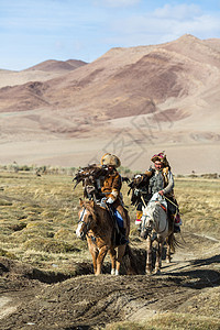 猎鹰人教她年轻女儿与猎食鸟类一起捕猎到西蒙古沙漠山的野兔SEP28图片