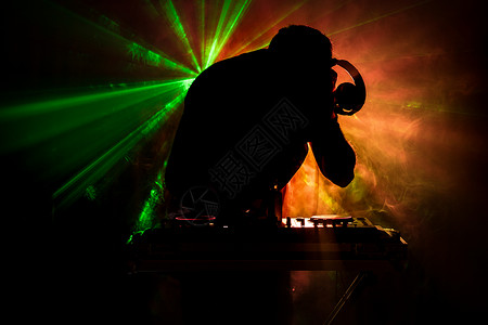 DJ之手调整dj甲板上的各种轨道控制频闪灯和雾背景图片