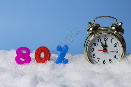 冬季折扣的概念时钟和80的数字在雪地背景图片