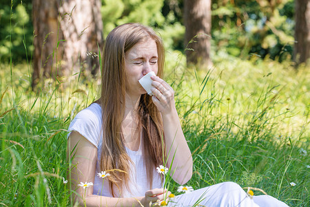 草地上的女人打喷嚏过敏的概念图片