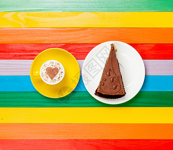 一杯咖啡卡布奇诺咖啡与彩虹背景上的蛋糕图片