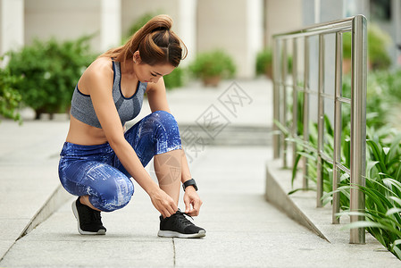年轻的女运动员在跑步前系鞋带图片