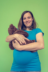 孕妇在绿色背景面前冒充一个假扮婴儿的胖玩图片