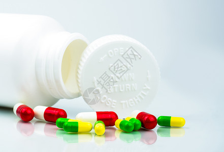 安全用药展架白色背景上的彩色药丸和带有空白和复制空间的塑料瓶儿童安全包装儿童抗药丸容器向下推并转动上限全球背景