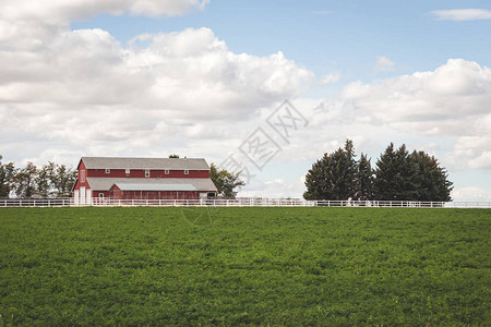 绿色田地和白色栅栏附近的红色和白色农舍图片