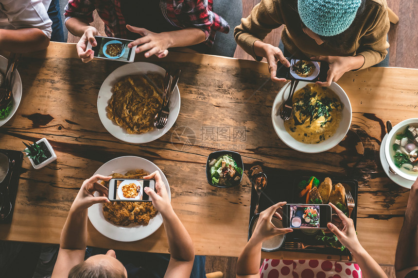 一群朋友在享用美食和饮料之前用手机拍照图片