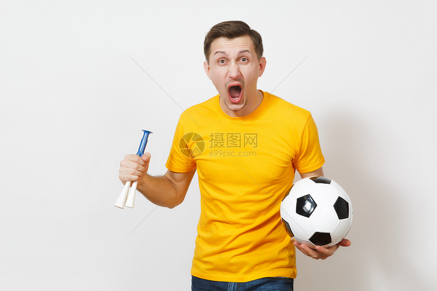 激发灵感的年轻有趣开朗的欧洲男子球迷或身穿黄色制服的球员拿着足球烟斗欢呼最喜欢的足球队在白色背景下被隔离运动踢足球图片