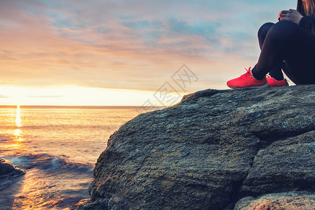年轻女孩坐在海边的岩石图片
