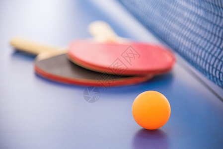 乒乓球的橙色球和两个红色和的木制球拍图片