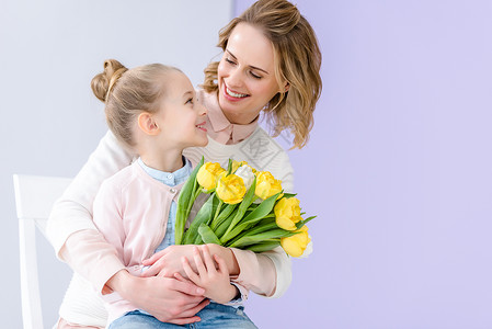 可爱的孩子拥抱母亲与郁金香花束图片