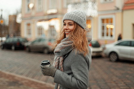 穿着复古时尚灰色冬衣针织时尚帽和时尚围巾的美丽快乐的年轻女子图片