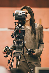 女摄像员在电影制片厂用相机拍摄电影图片